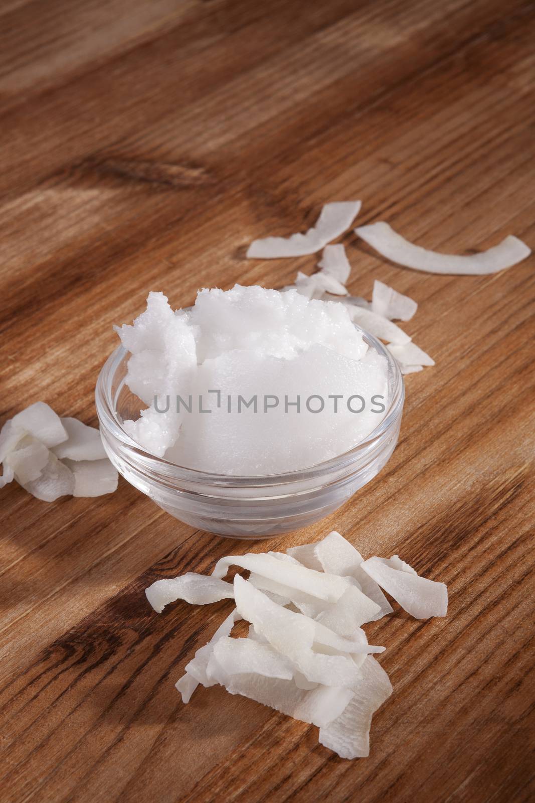 Organic coconut oil with coconut flakes on wooden background. Healthy vegan cooking and eating.