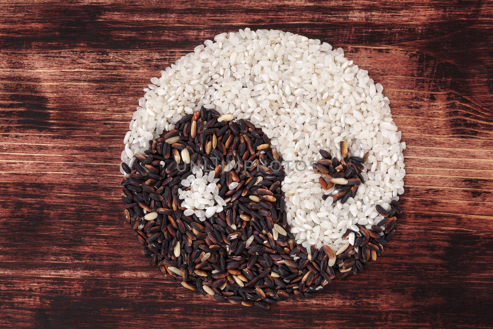 White and wild rice shaped as Yin yang symbol on dark wooden background. Traditional chinese eating and culture.