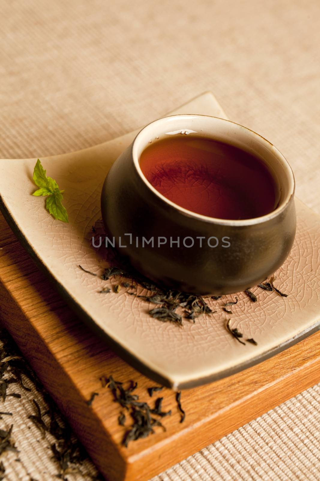Black tea still life in a beautifull ceramic pot with mit and dry tea leaves.