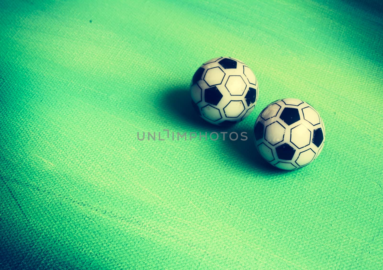Two toy footballs on green canvas by ArtesiaWells