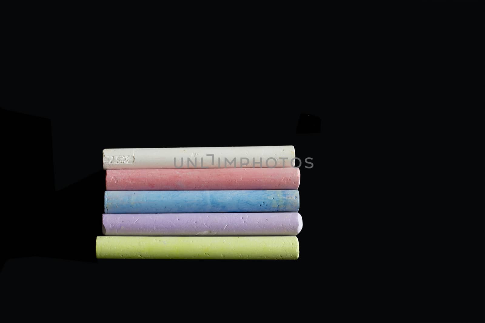 Colored chalks isolated on black. Chalks in light green, violet, blue, red and white isolated on black.