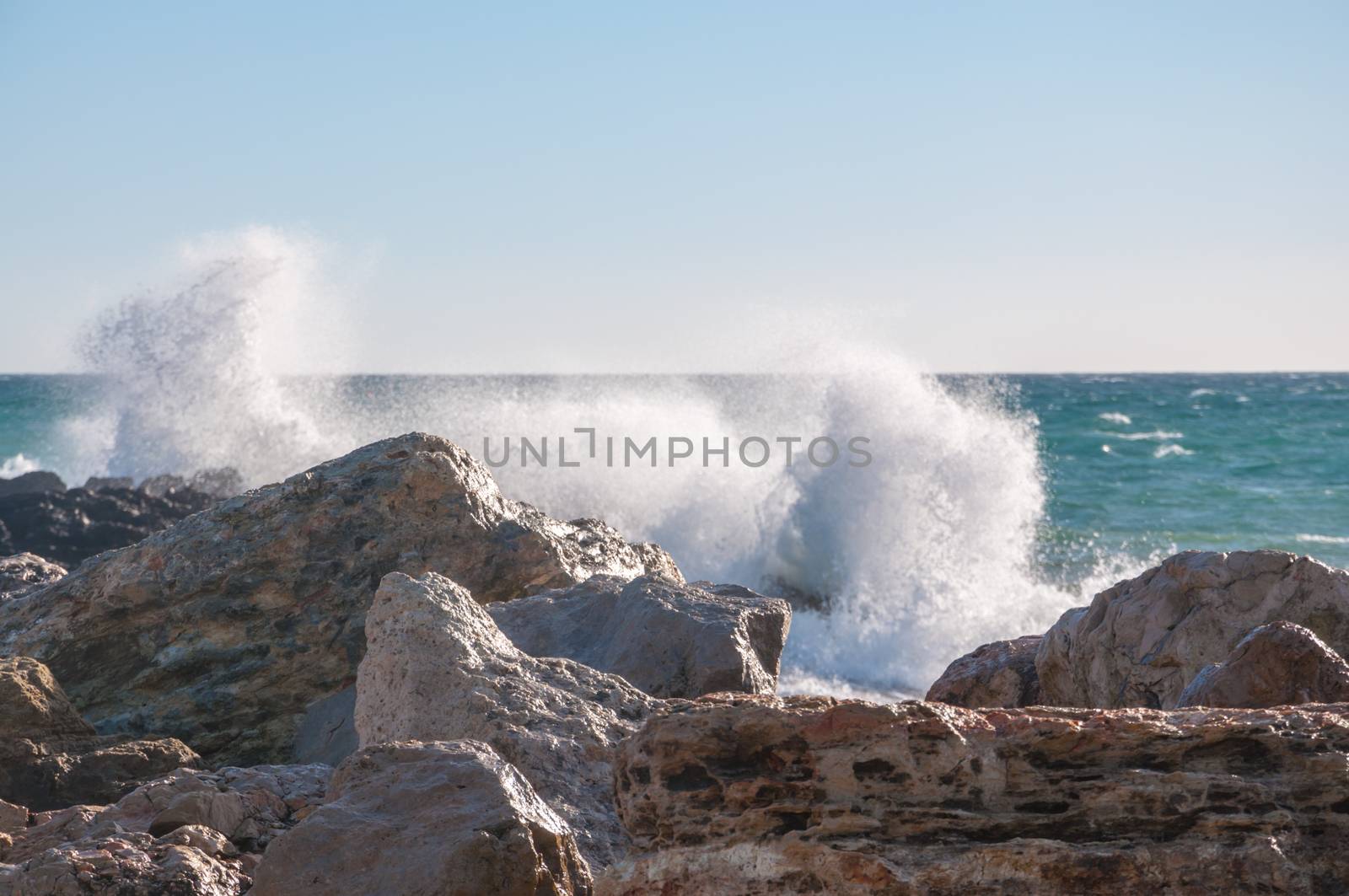 Crashing splashing wave. Wave breaking and sending seaspray onto limestone rocks, Majorca, Balearic islands, Spain.