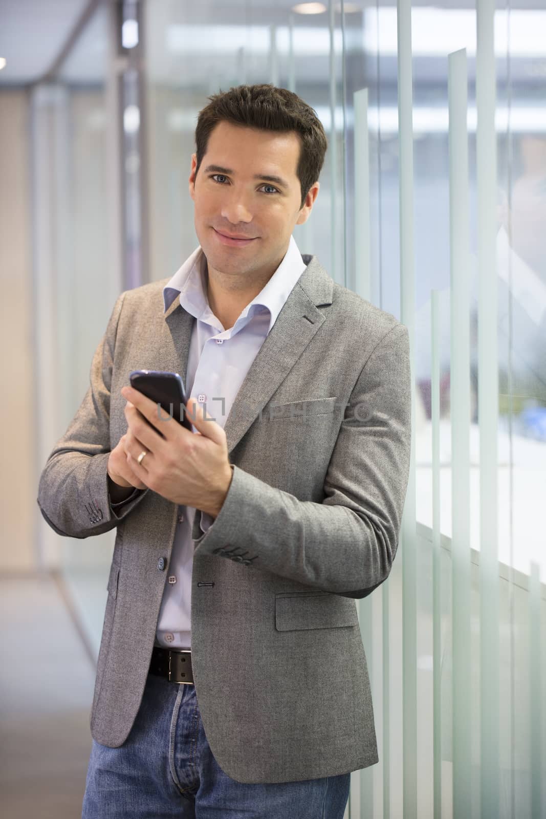 Handsome Business man at the office on phone, sms, e-mail by LDProd