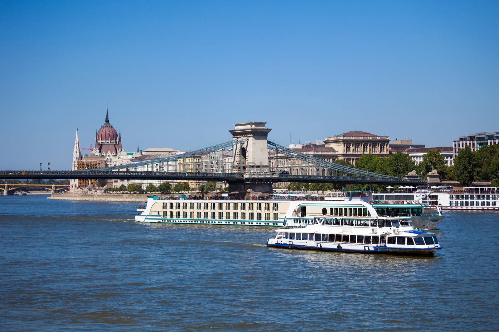 Cruise ships on Danube river with Chain Bridge in front  and Parliament Building in the background, Budapest.
