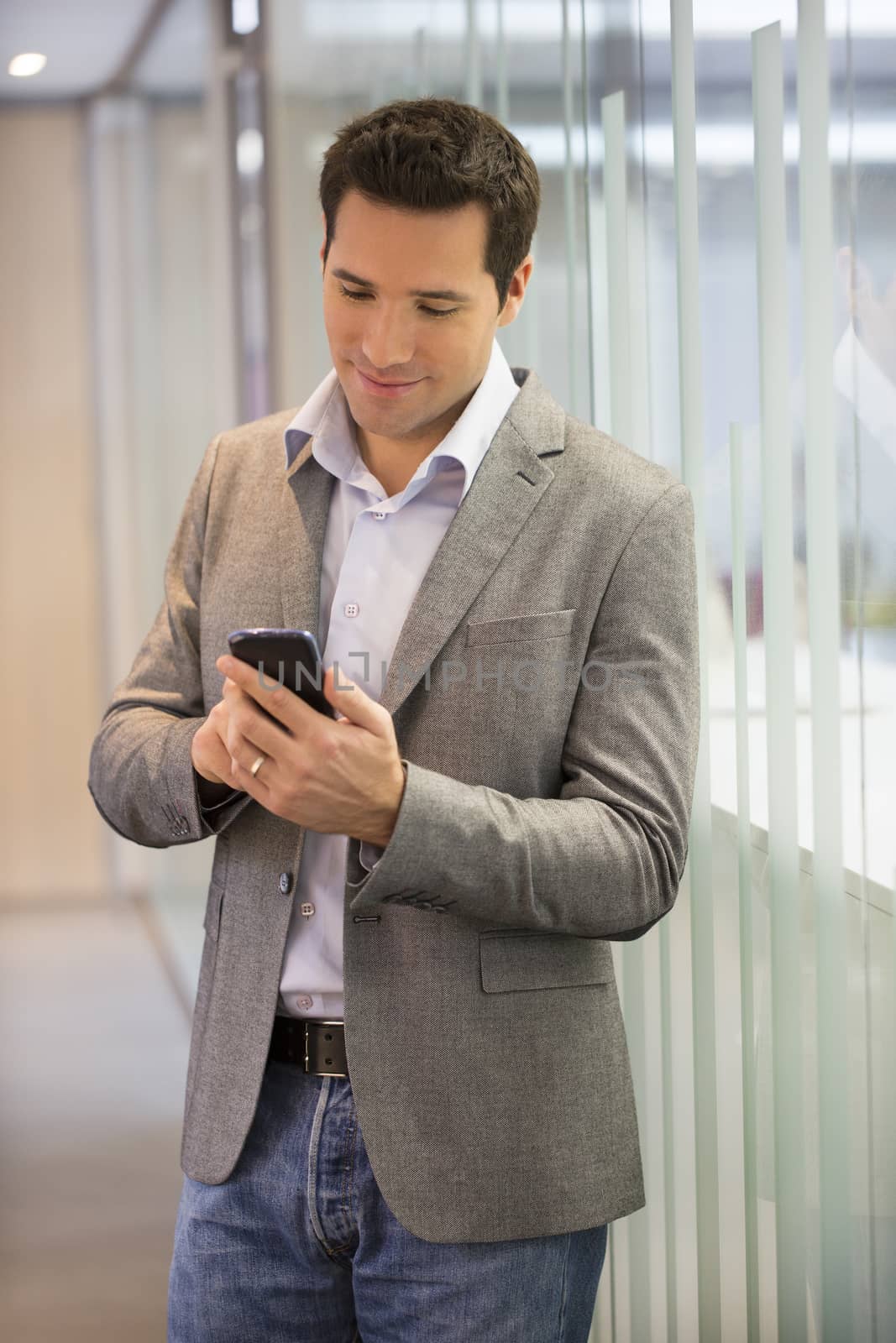 Handsome Business man at the office on phone, sms, e-mail by LDProd
