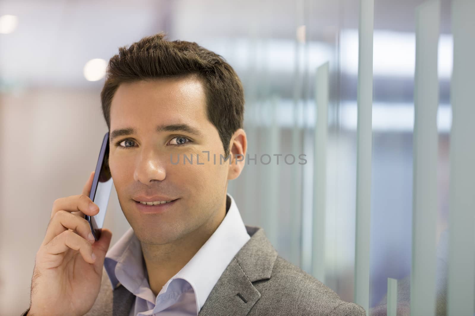 Successful businessman talking on cell phone, looking camera by LDProd