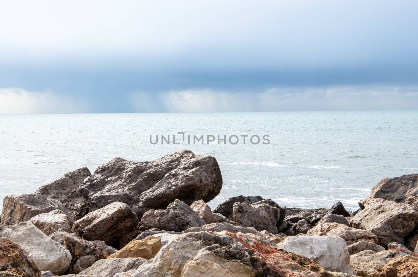 Limestone rocks, pale turquoise ocean and cloud with rain.