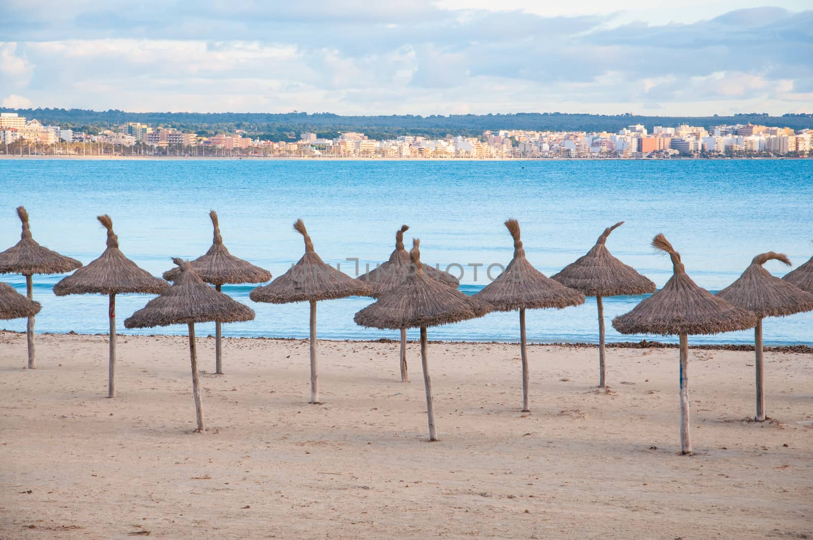 Straw umbrellas on empty beach, Playa de Palma, Majorca, Balearic islands, Spain in February.