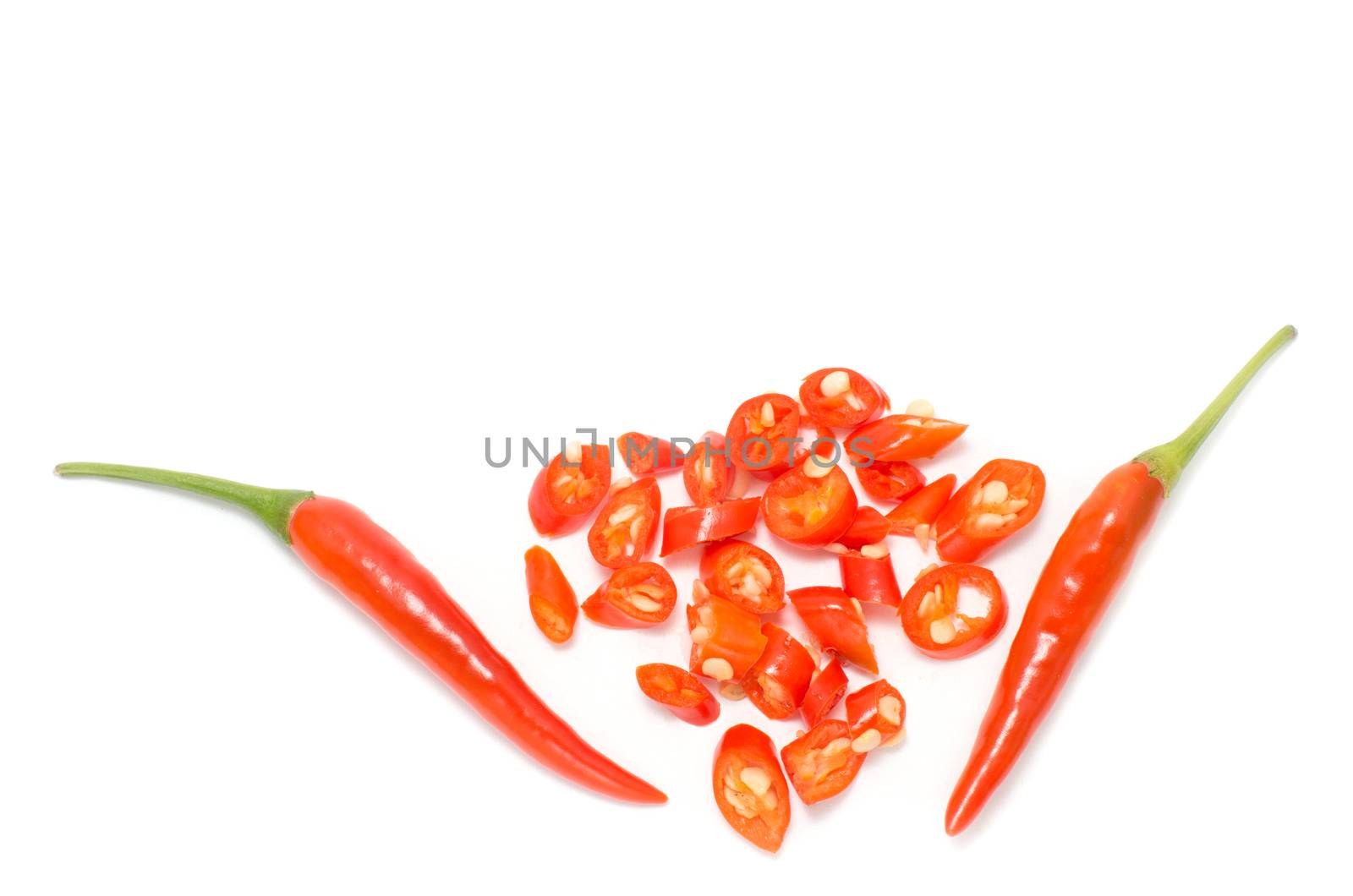 Two red chili peppers with small slices on white background