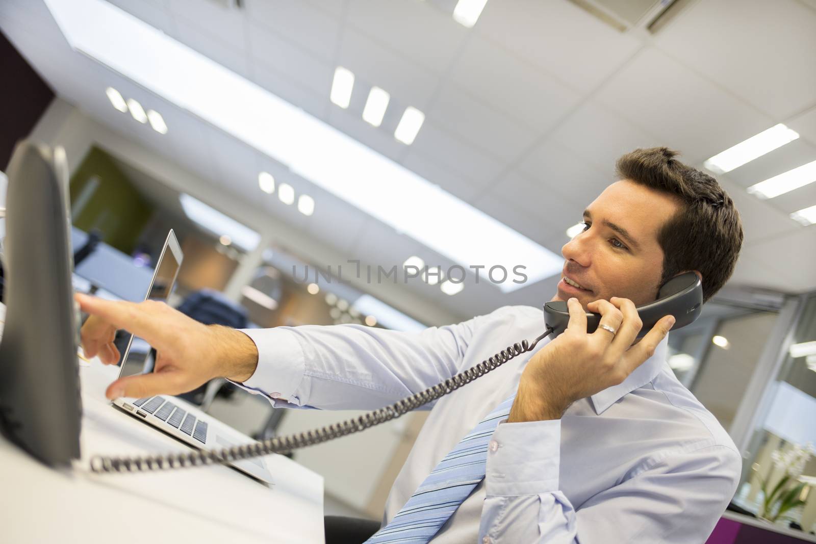Portrait of smiling businessman at phone in office by LDProd