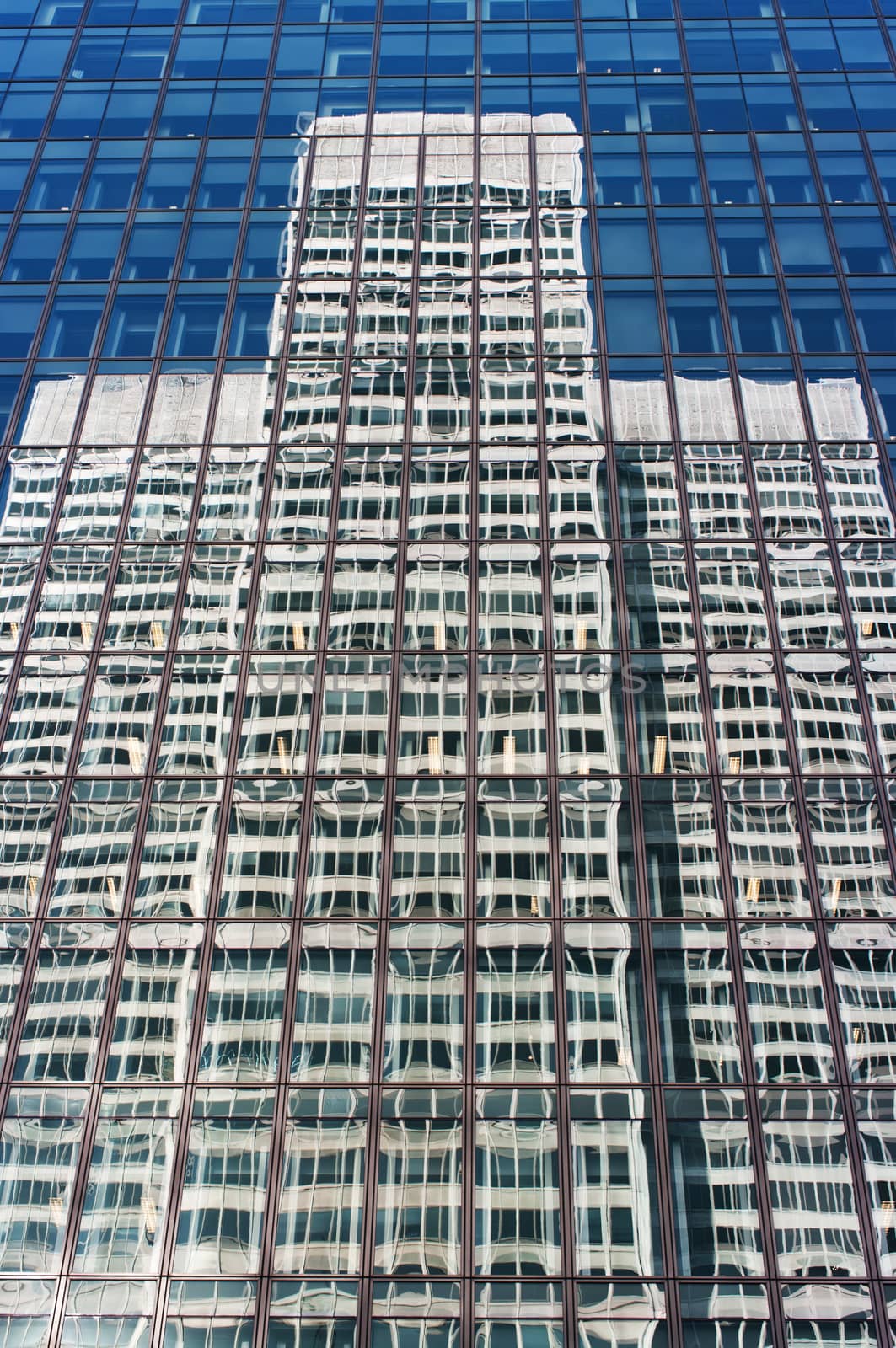 exterior of contemporary glass business center with another building reflected on