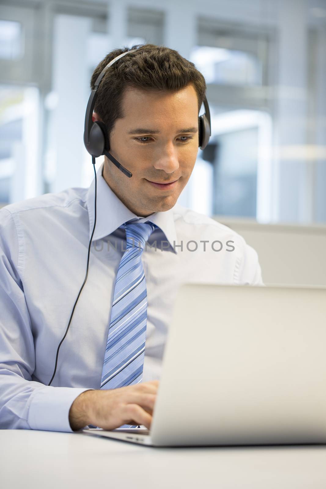 Businessman in the office on the phone with headset, Skype by LDProd