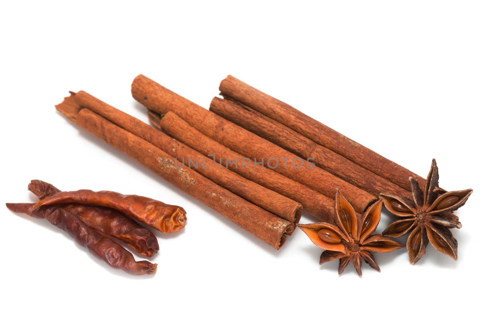 Cinnamon sticks, star anice and dried chilis on white background