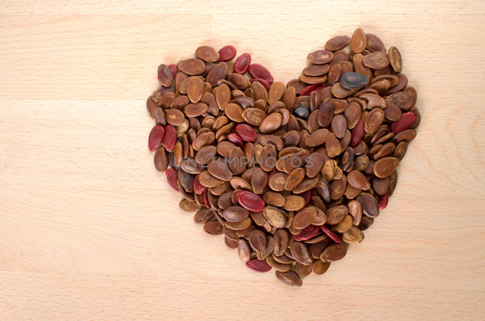 Heart shape red rosted watermelon seed on wooden cut board