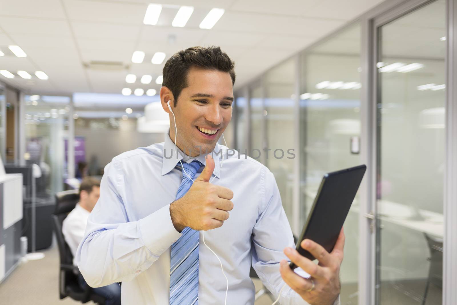Smiling Businessman chatting on internet with Tablet Pc, office Background