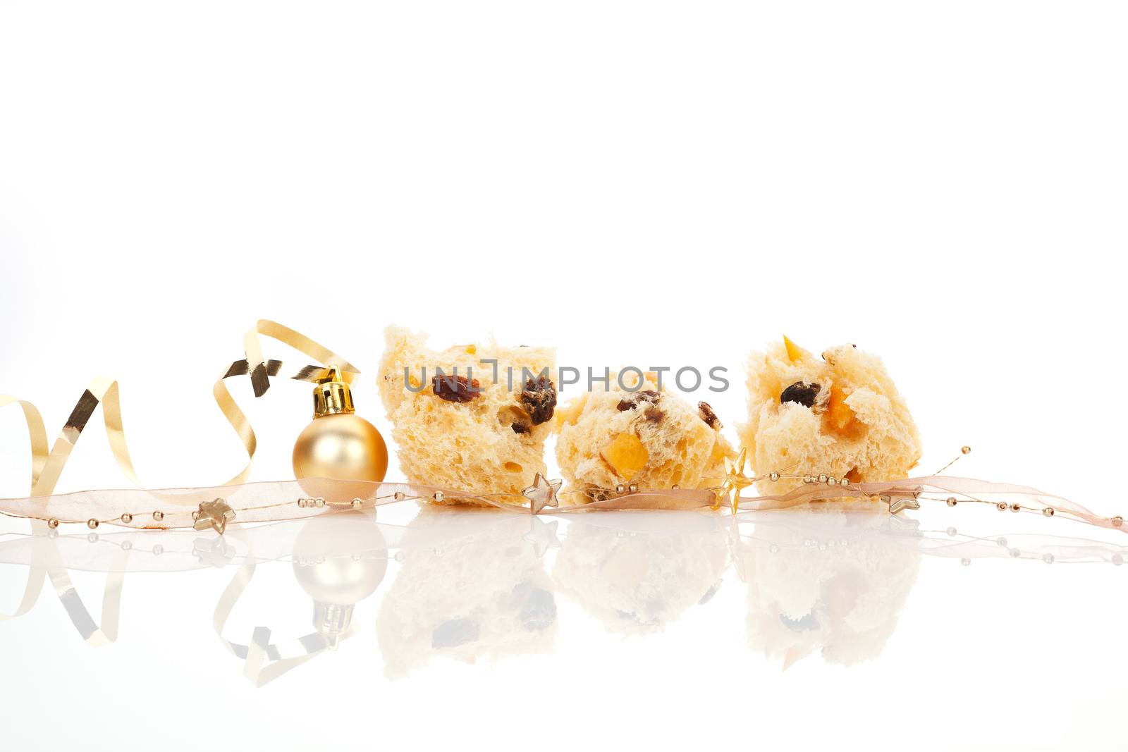 Luxurious panettone pieces with golden ribbon and christmas balls over white background. Festive background.