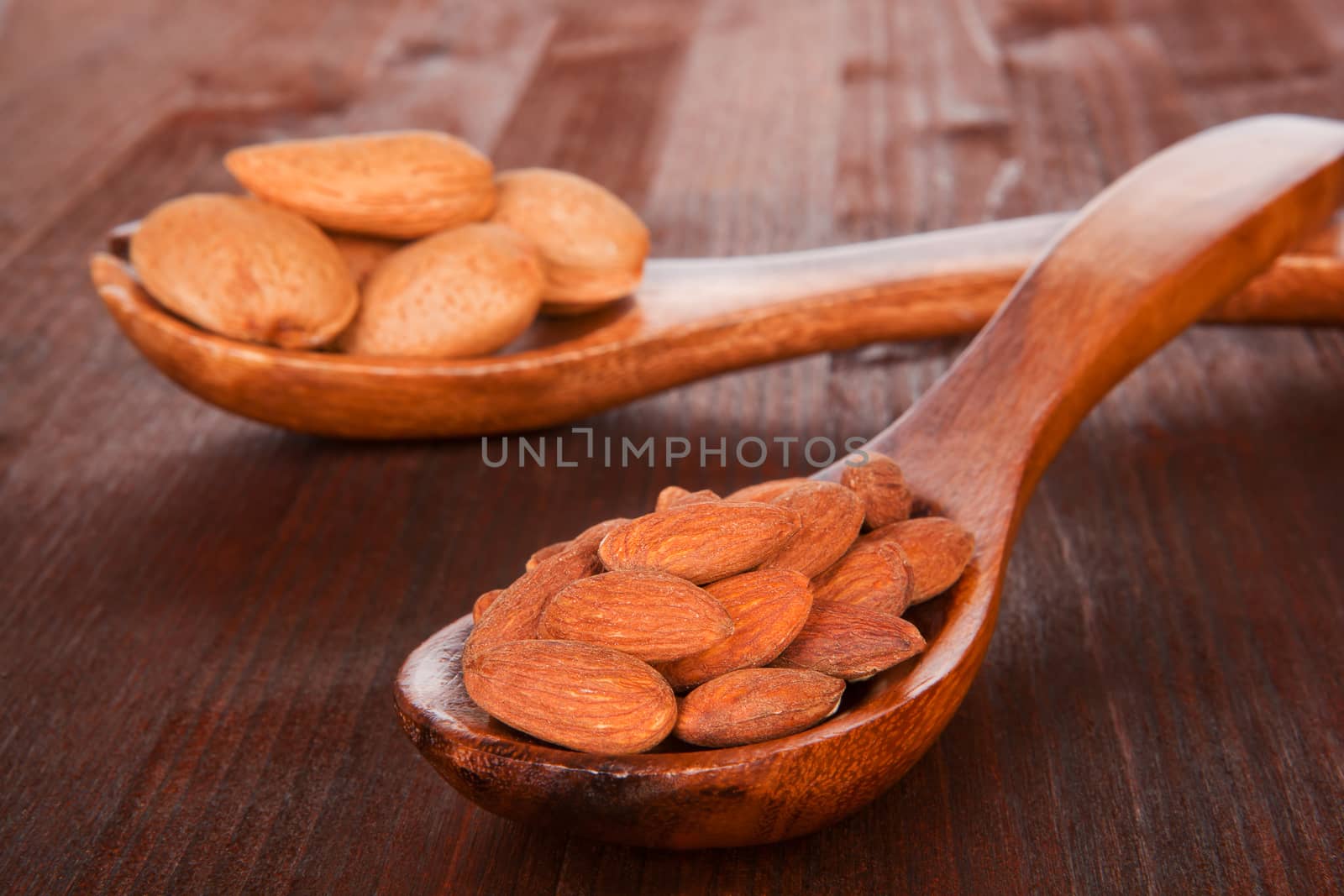 Almond nuts and kernels on wooden spoon on wooden background. Culinary nuts concept.