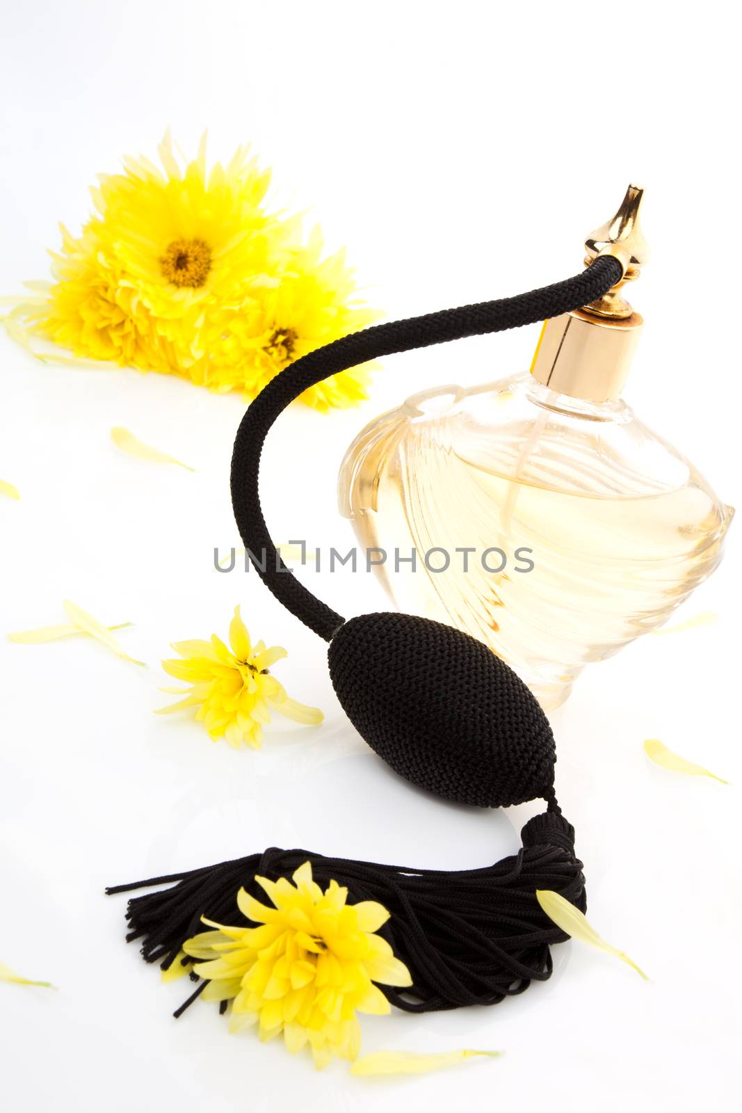 Vintage perfume bottle atomizer with yellow flowers isolated on white background. Feminine beauty concept.