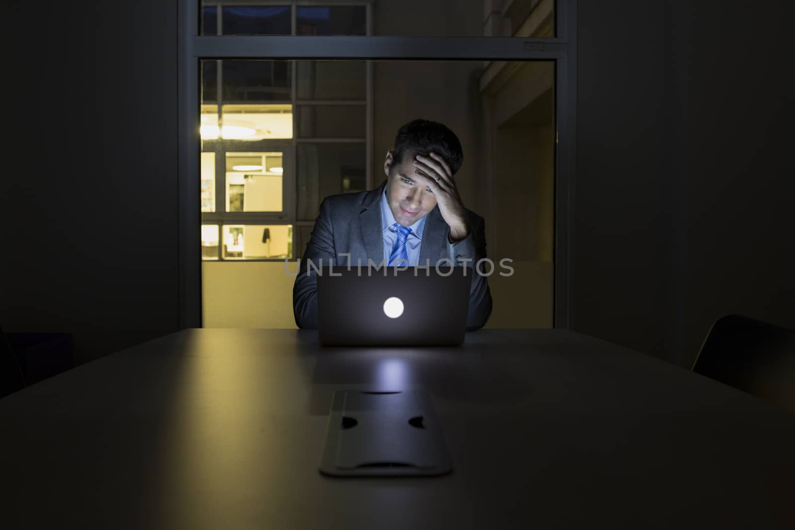 Businessman working late in his office on laptop, night light by LDProd