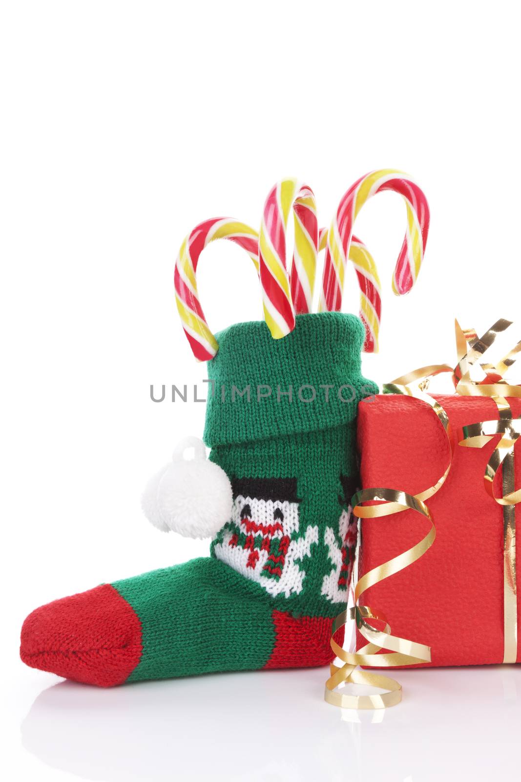 Traditional christmas sock with red gift, candy cane and golden ribbon isolated on white background. Red and green traditional xmas.