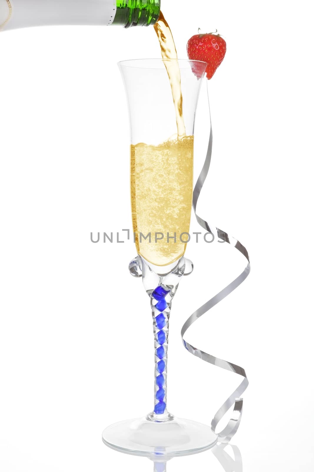 Pouring golden champagne into a glass with silver ribbon isolated on white. Luxury new year concept.