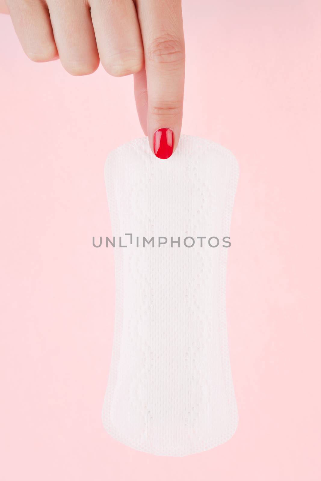 Female hand with red fingernails holding clean pantyliner. Feminine hygiene concept.