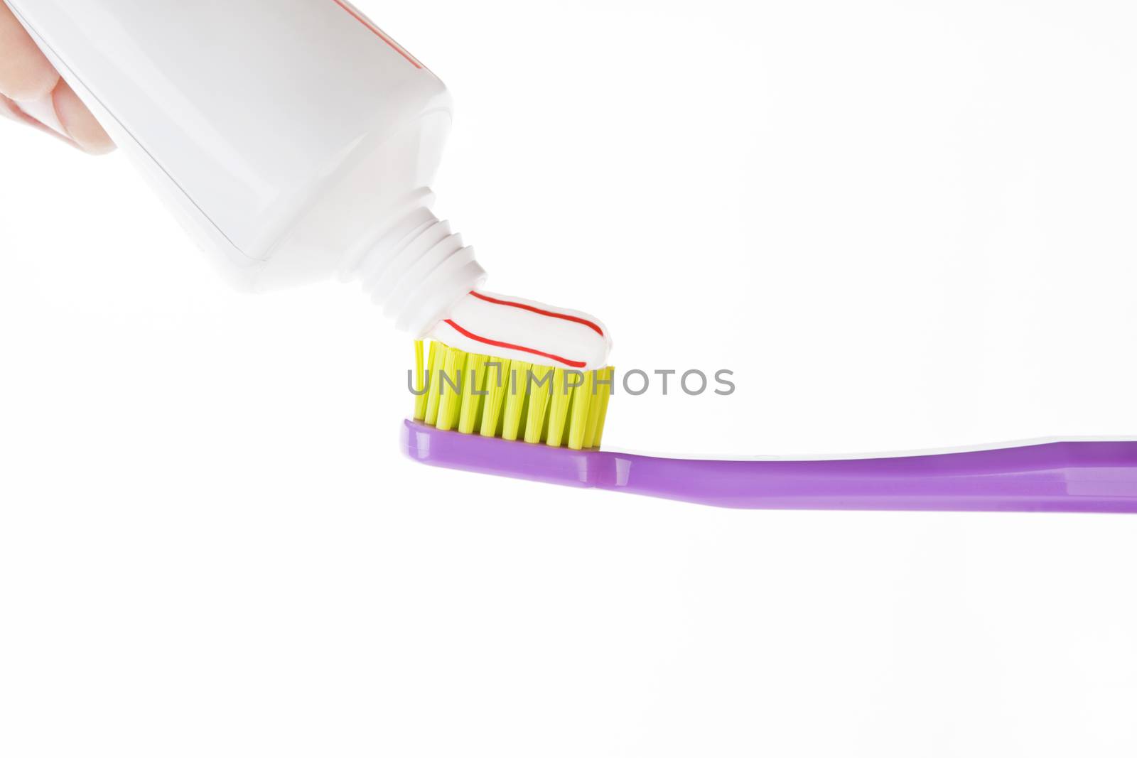 Red and white striped toothpaste on green and purple toothbrush isolated on white background. Dental care concept.