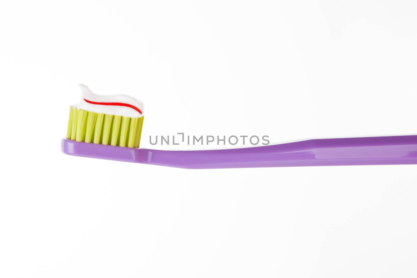 Purple toothbrush with striped red and white toothpaste isolated on white background. Dental hygiene concept.