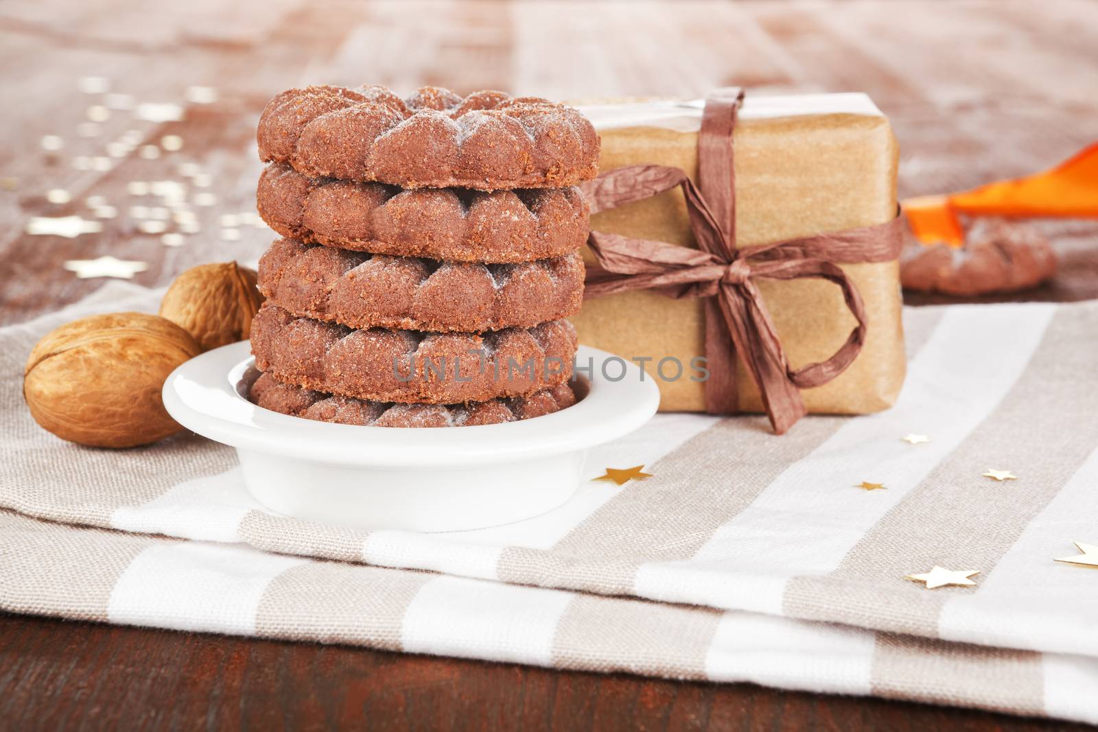 Chocolate christmas cookies with nuts and ecologicaly wrapped gift on dark wooden background. Christmas giving concept.