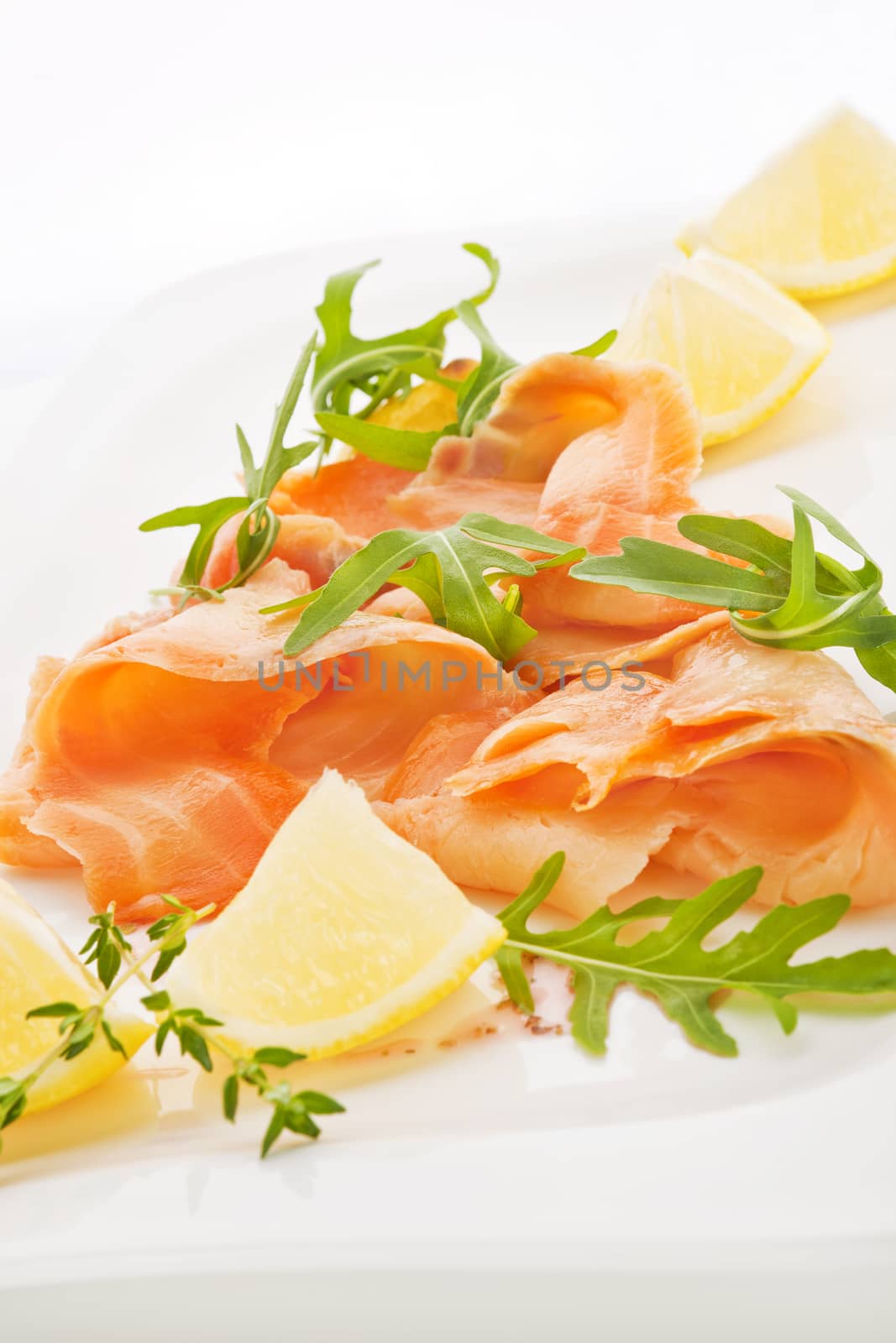 Raw fresh salmon with fresh arugula, thyme and lemon. Luxurious culinary eating.