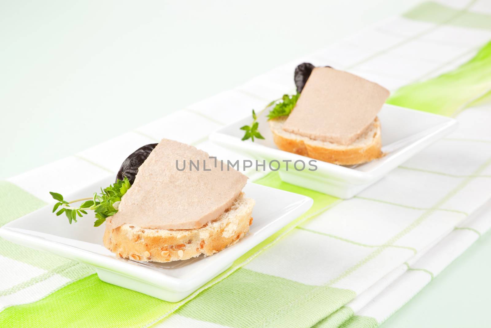 Luxurious culinary eating. White bread with pate, herbs and dried plumb. 