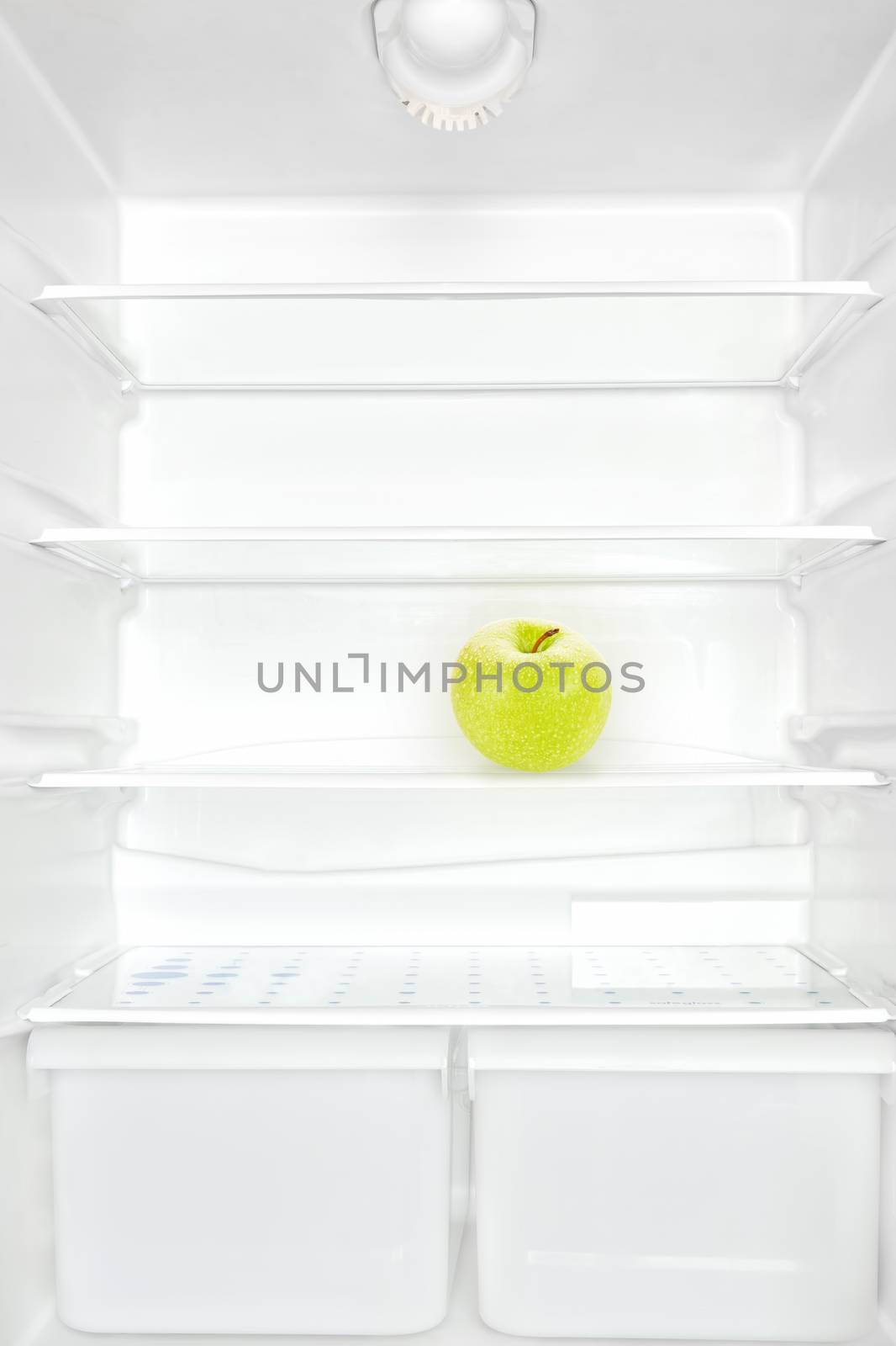 One apple in open empty white refrigerator. Weight loss diet concept.