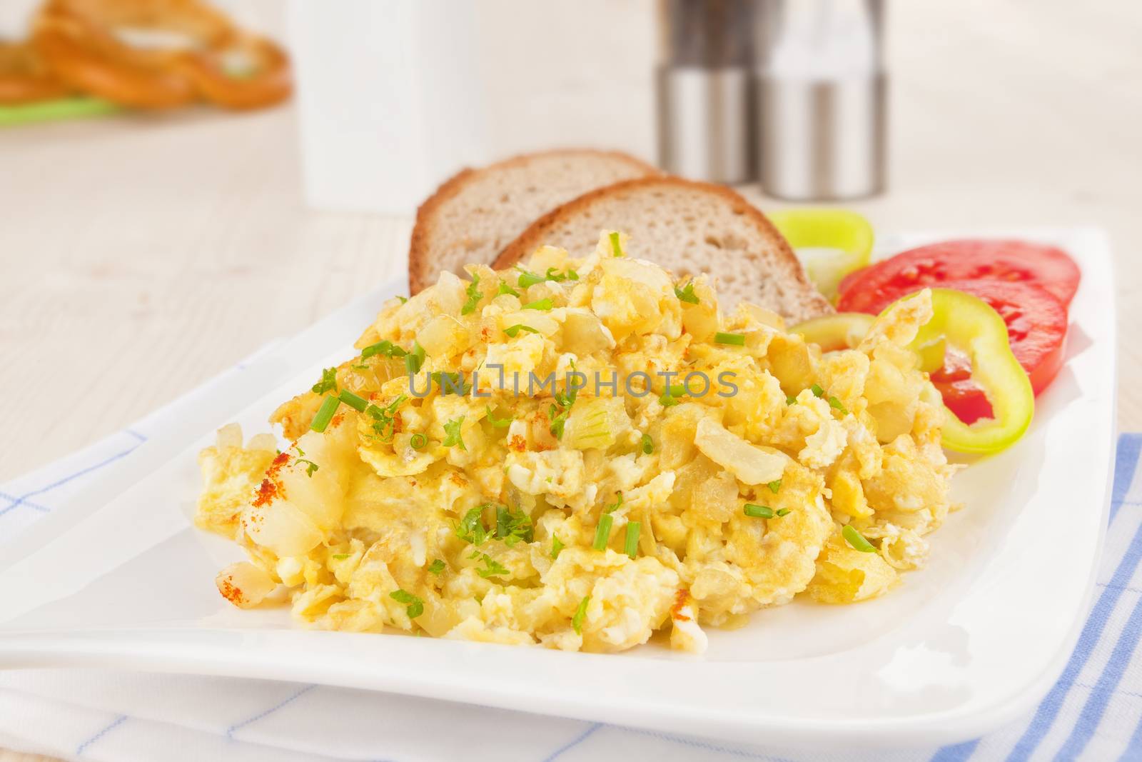 Scrambled eggs with brad slices and fresh vegetable. Luxurious breakfast.