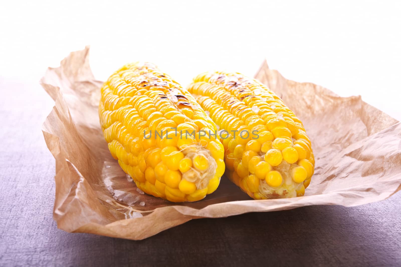 Boiled and roasted golden corn on a piece of baking paper. Culinary healthy vegetable.