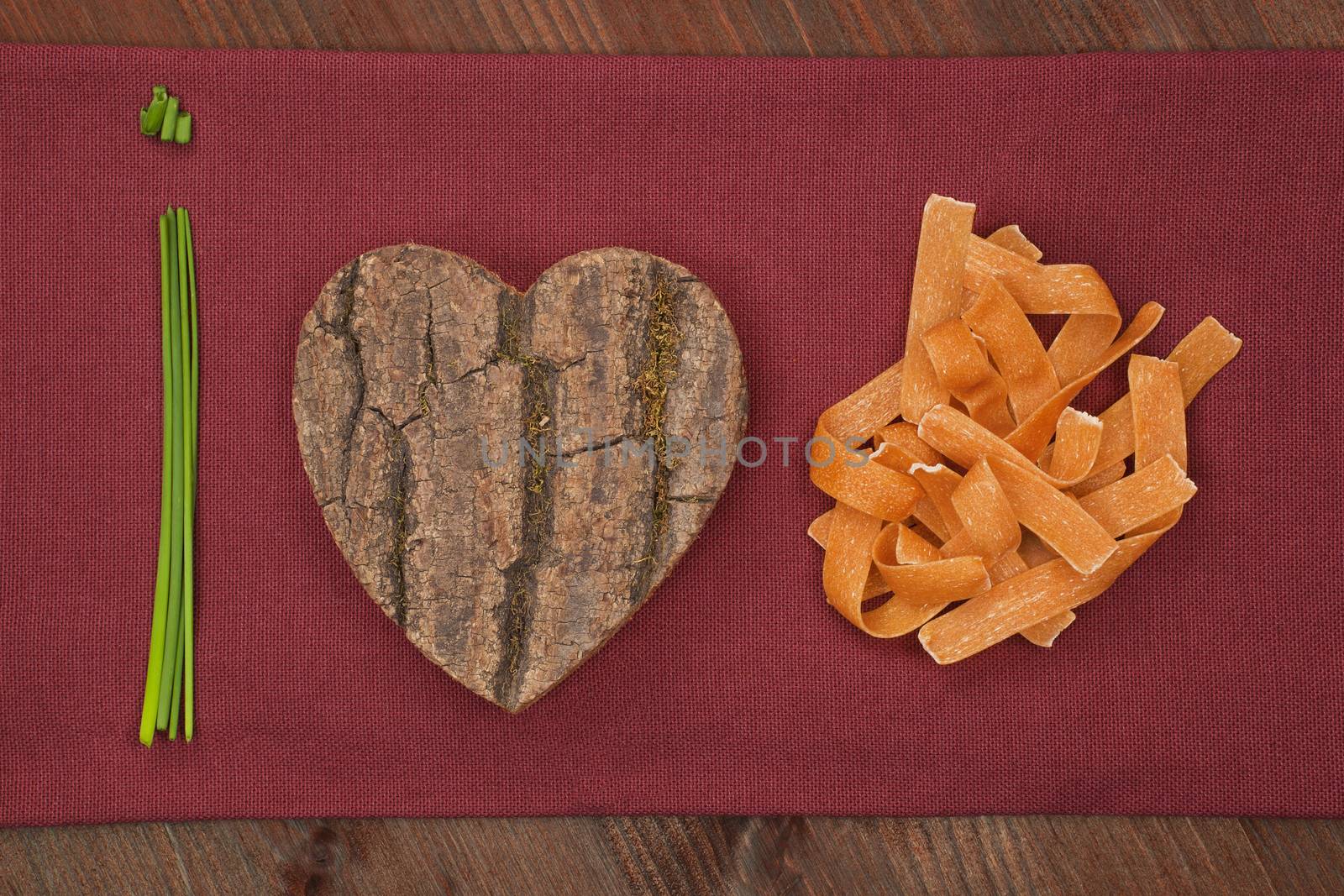 I love pasta made of chive, wooden heart and pasta on burgundy cloth. Healthy eating background.