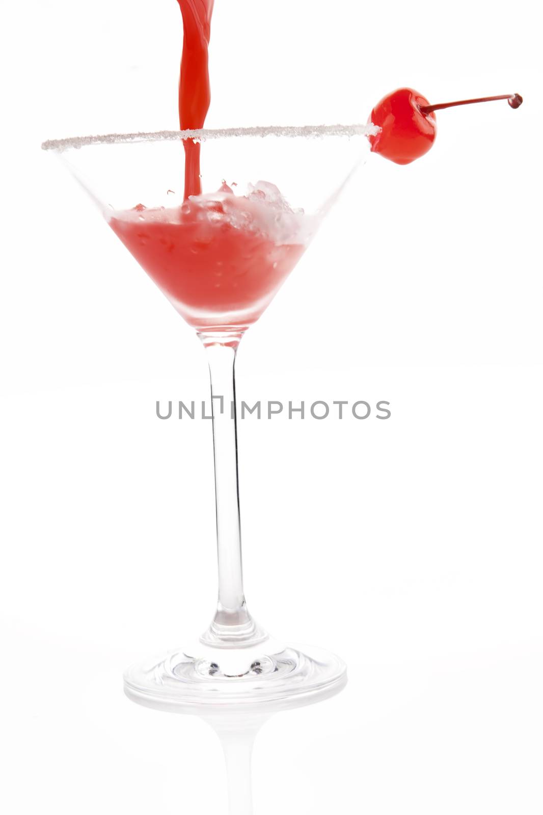 Pouring fresh fruity cocktail into cocktail glass decorated with cherry isolated on white background. Delicious drink.