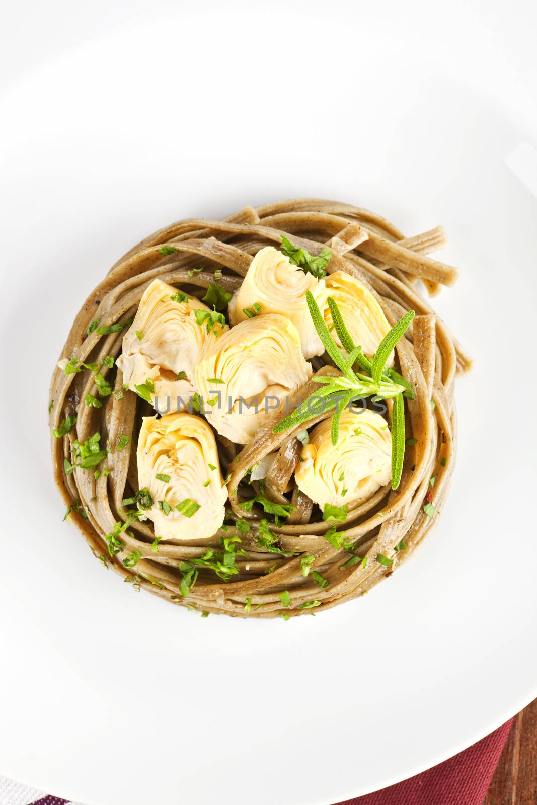 Luxurious tagliatelle with artichokes and fresh herbs on white plate. Luxury dining.