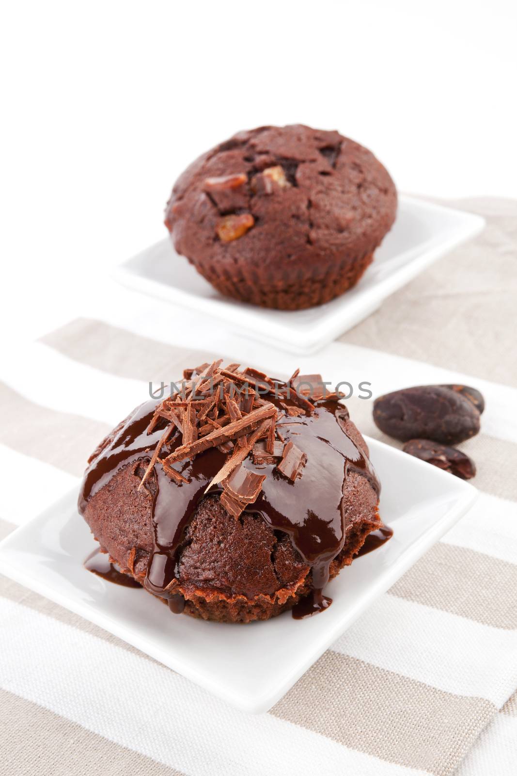 Luxurious chocolate muffins with chocolate garnish in white bowl on kitchen cloth. 