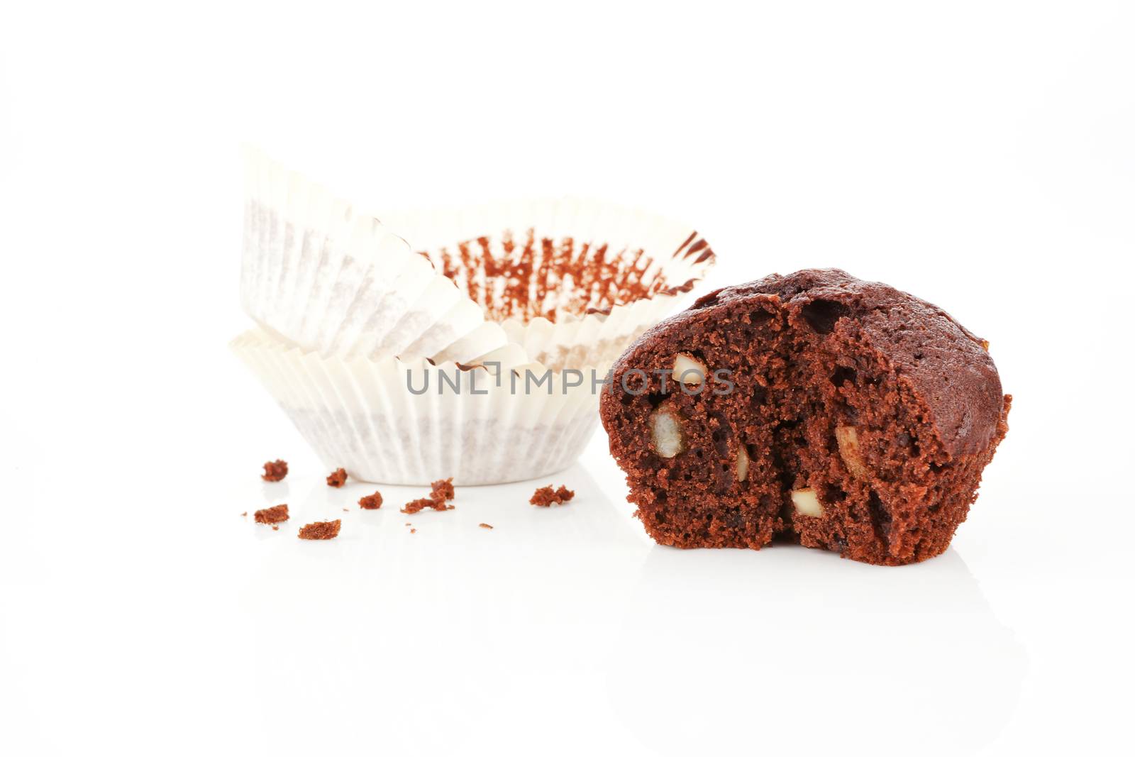  Chocolate muffin cross section isolated on white. Paper and crumbs in background.