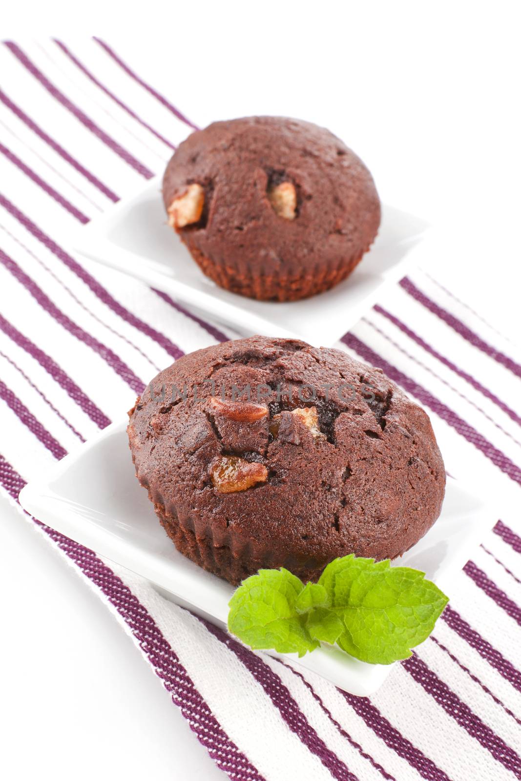 Luxurious chocolate muffins decorated with fresh mint leaf in white bowls. Culinary sweets.