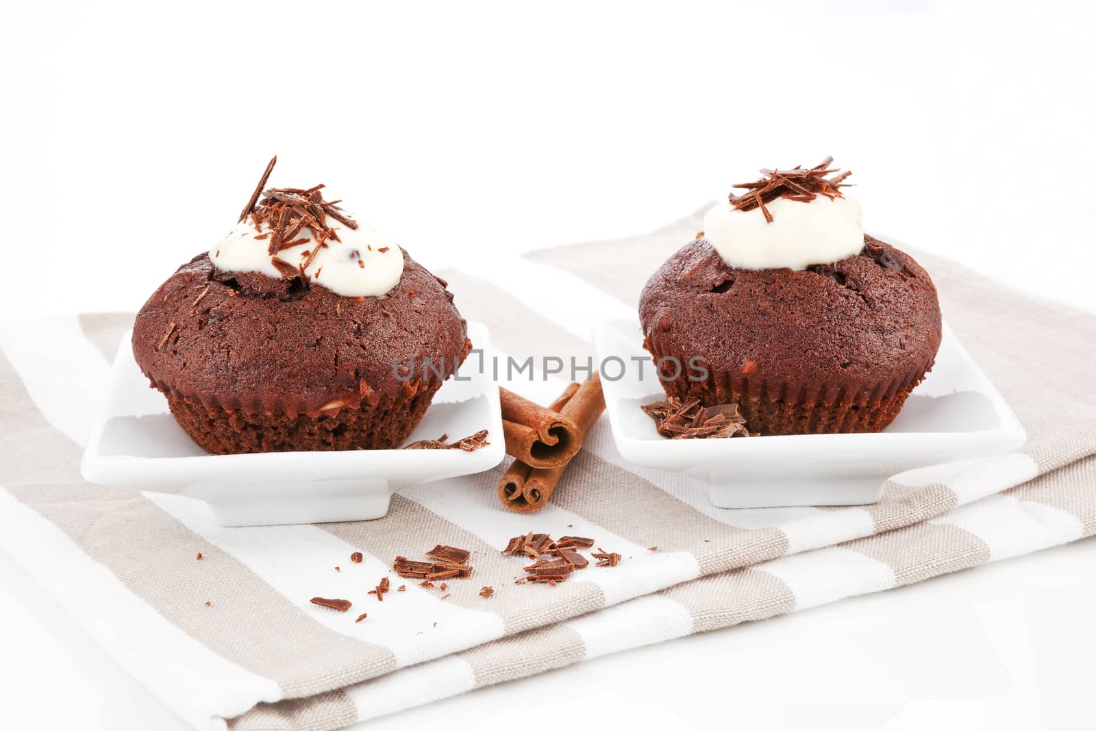 Two delicious mouthwatering chocolate muffins with cream and chocolate.