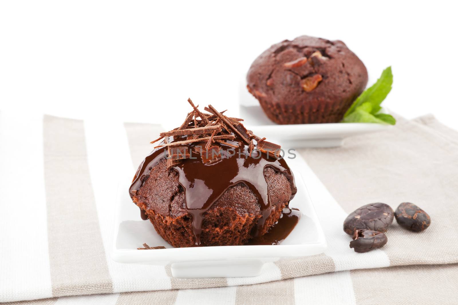Delicious chocolate muffins with chocolate garnish and chocolate beans on kitchen cloth. Gourmet sweet food.