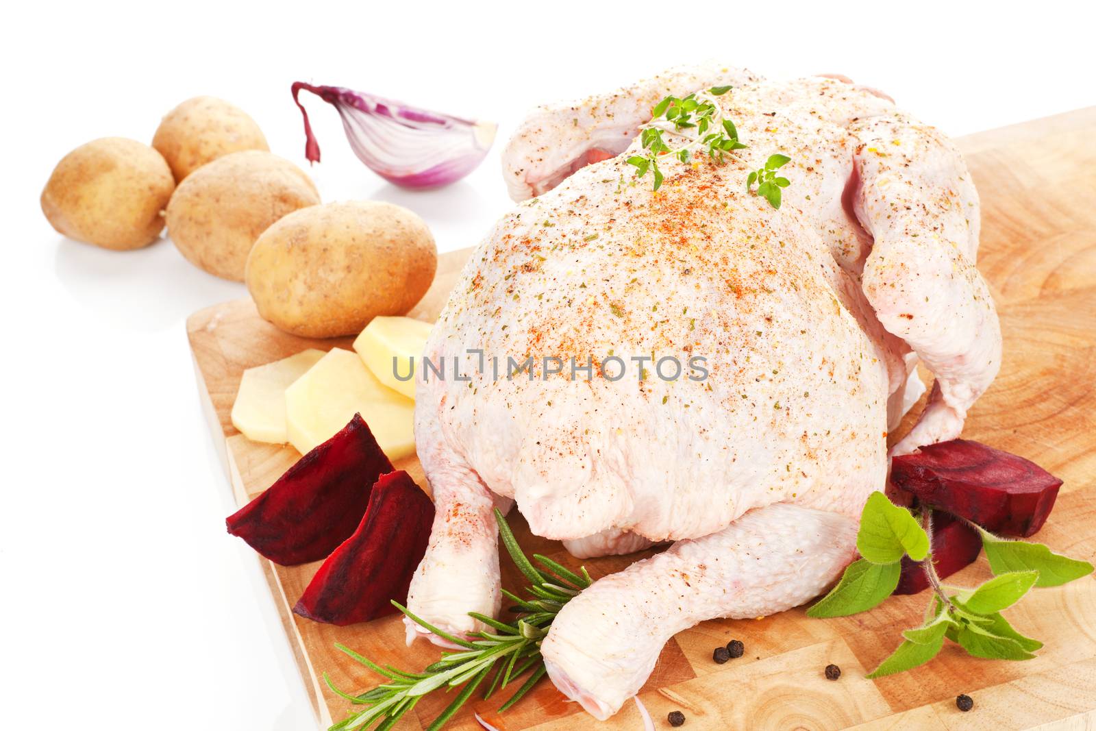 Delicious raw chicken on wooden board with fresh vegetable and herbs prepared for cooking.