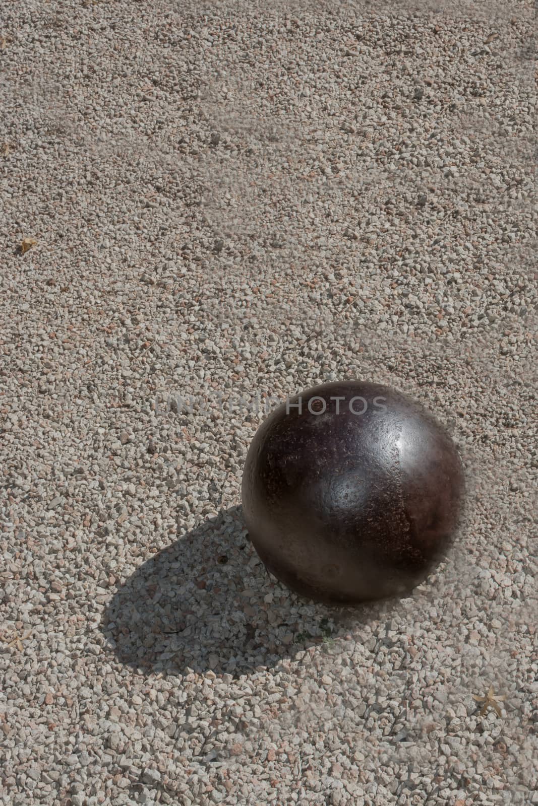 Iron ball on gravel with shadow