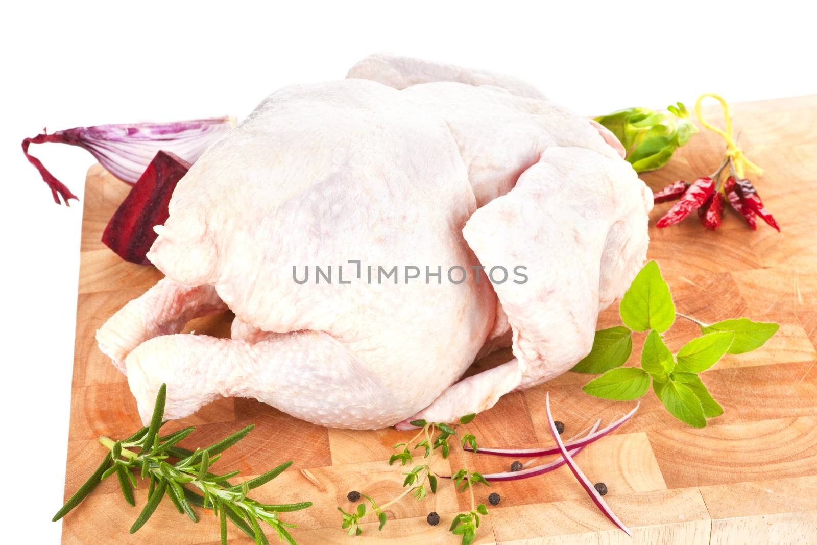 Whole raw chicken on wooden board with fresh herbs, spices and vegetable. Poultry background.