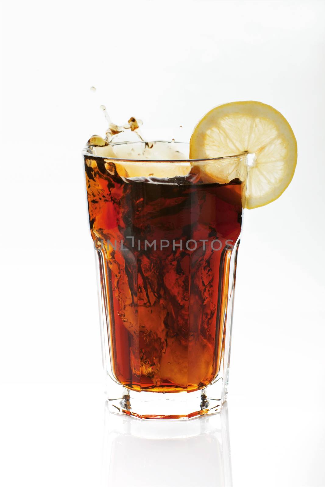 Cola with lemon splashing in glass isolated on white background.