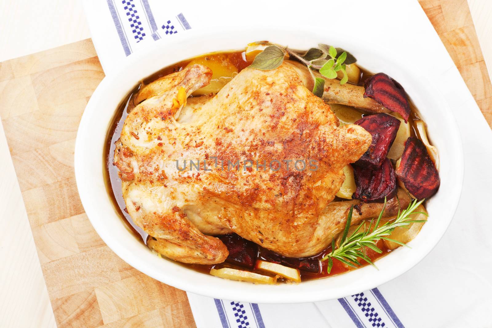 Luxurious golden baked chicken in white oval baking dish prepared for eating. Top view. 