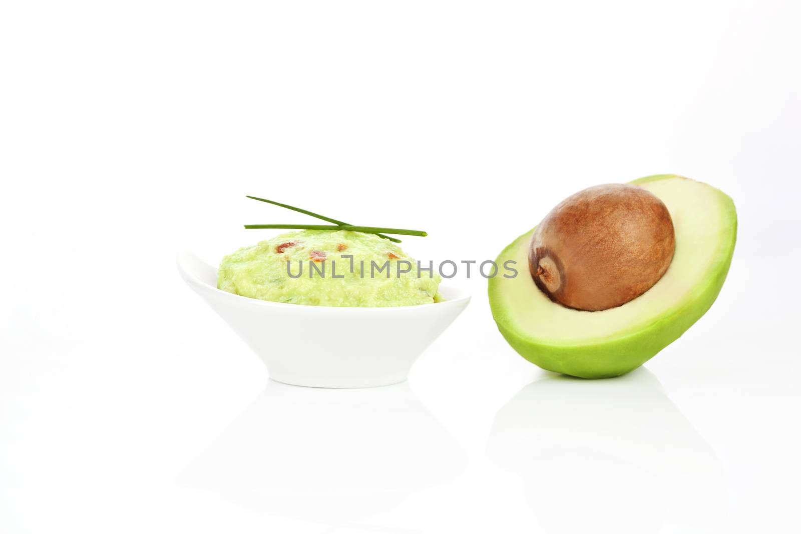 Avocado dip guacamole and fresh avocado half isolated on white background.
