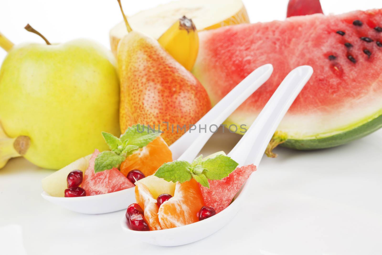 Delicious fruits pieces on white spoon. Healthy summer fruit background. Eat right, exercise regularly, die anyway. 