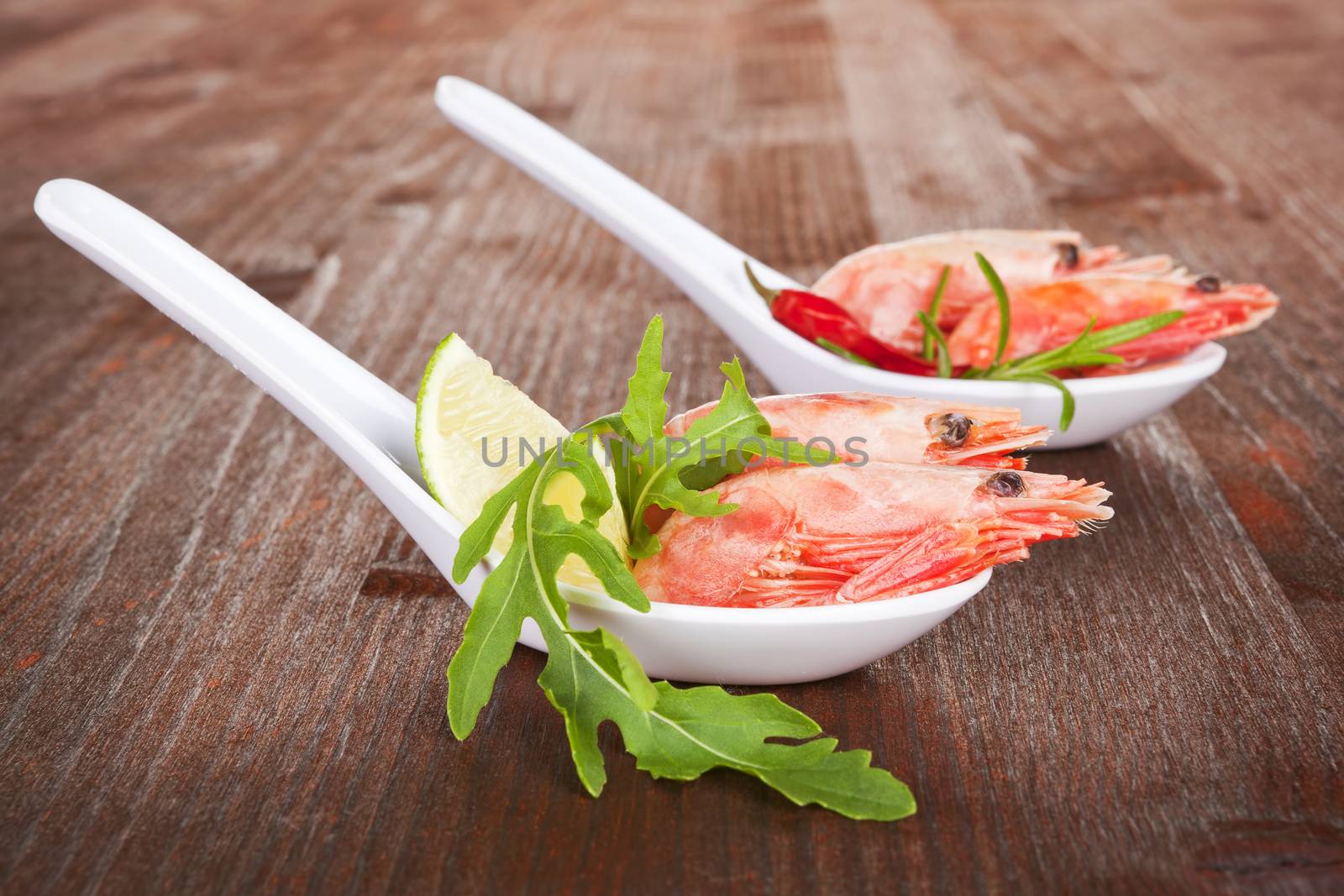 Delicious shrimps on spoon on dark wooden background. Luxurious seafood.